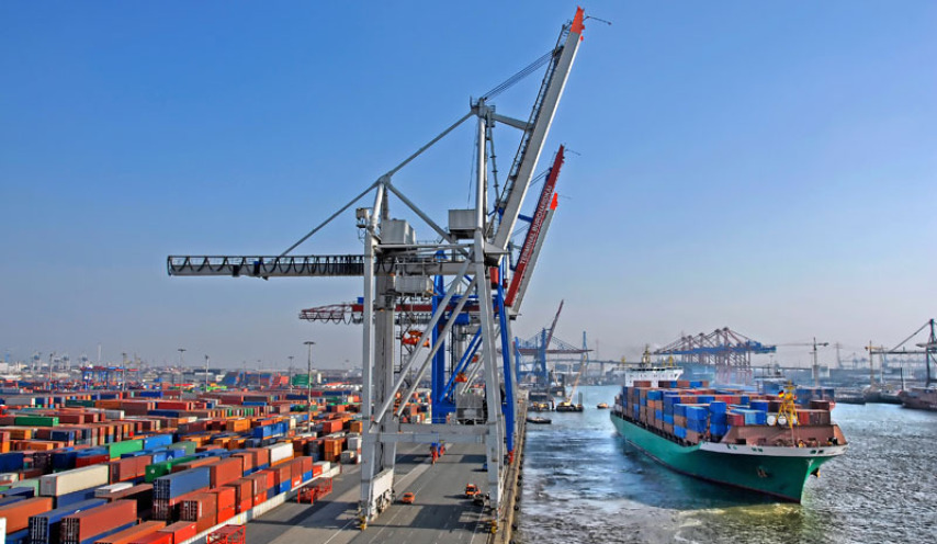 Ein Blick über einen Teil des Hamburger Hafens. Rechts fährt ein riesiges Containerschiff, links sieht man Krananlagen und links davon hunderte Container.